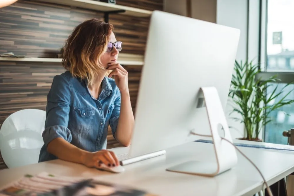 A woman examines her computer with managed IT information.