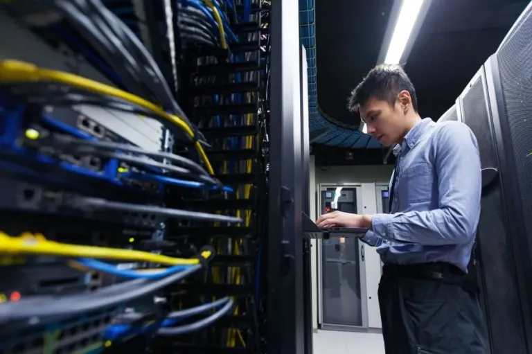 A man operates testing equipment in a server farm for managed IT uses.