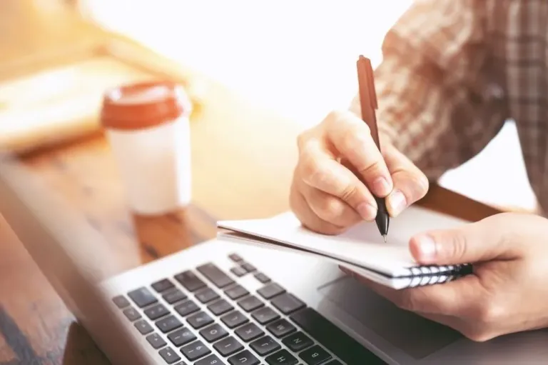 A managed IT professional working on a laptop and taking notes.